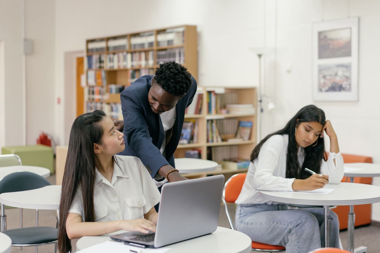 Students receiving guidance from a teacher in a well-equipped classroom.